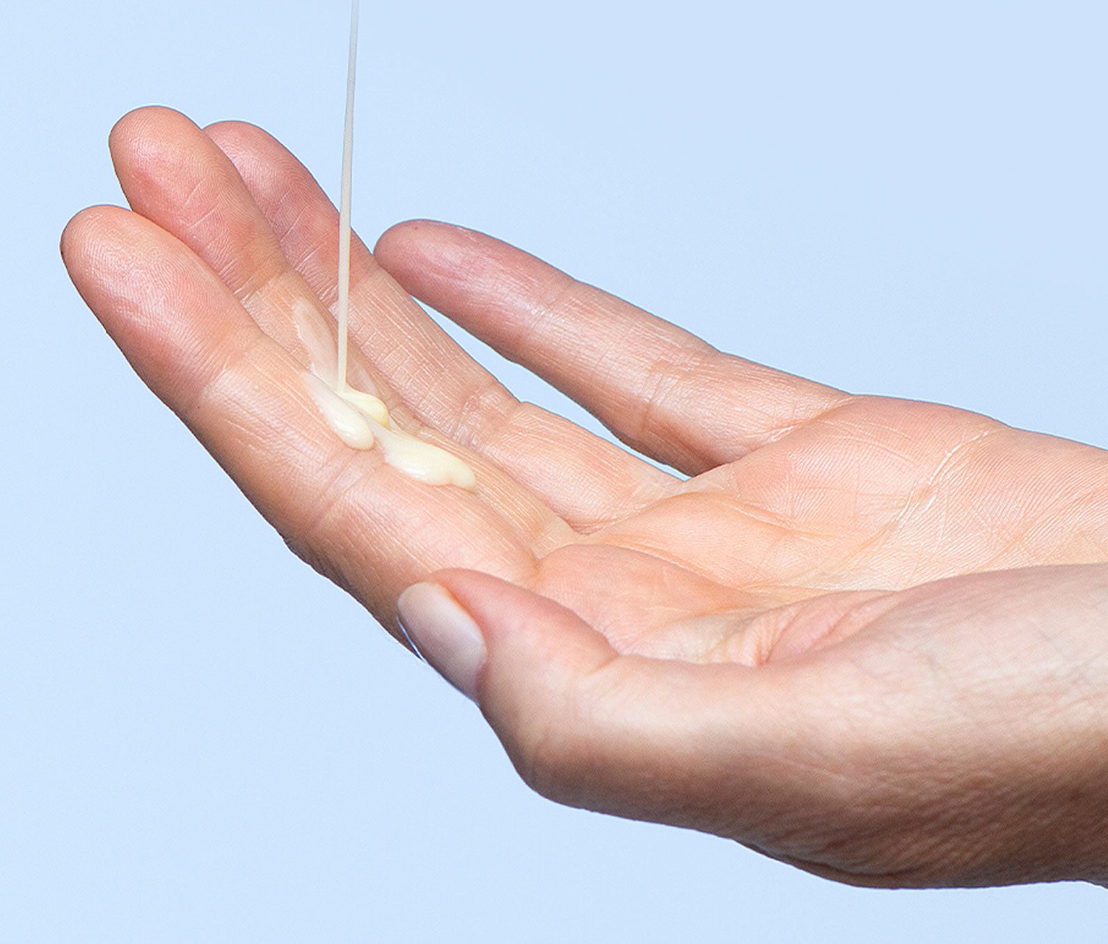 Serum dispensed into a hand on a light background