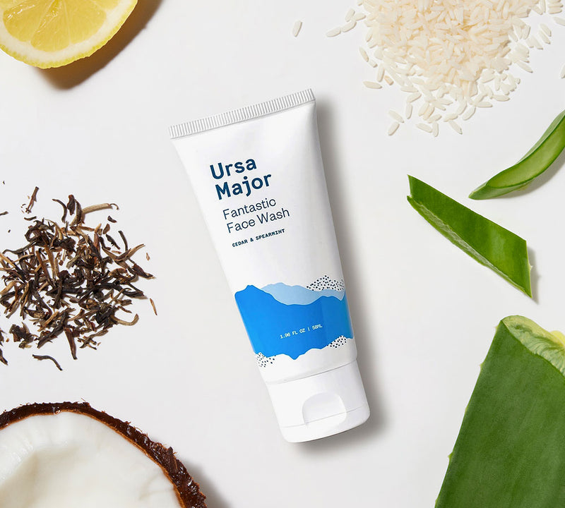 Ursa Major Fantastic Face Wash tube surrounded by natural ingredients on a white background