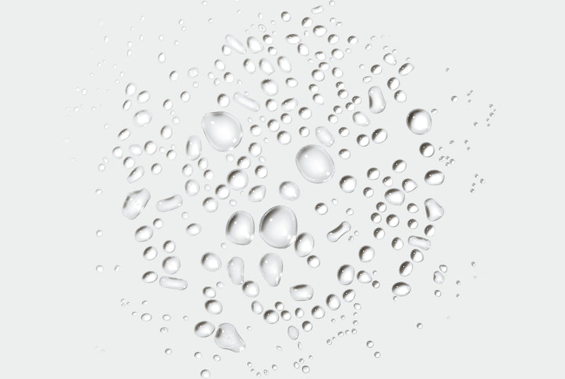 Clear droplets of sprayable deodorant on a grey background
