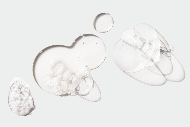 Close-up of clear, bubbling Shampoo on a light gray background