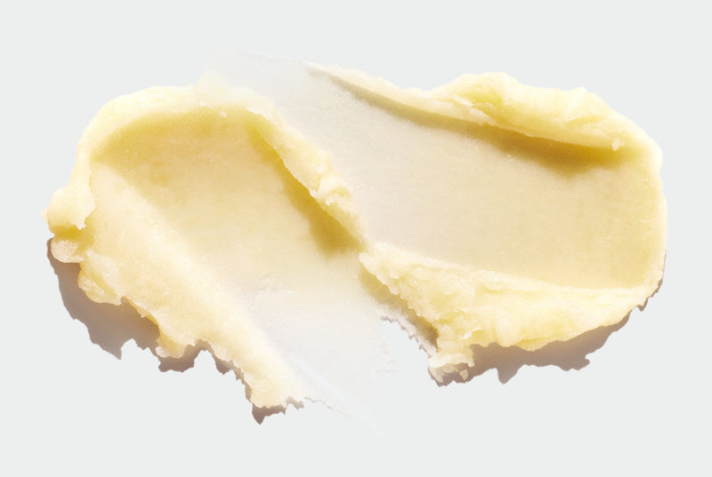 Two smears of thick Lip Balm on a white surface