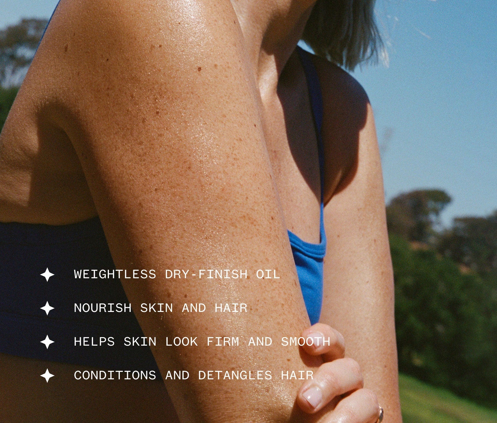 Image of woman spreading Dry Oil onto her skin with text about weightless dry-finish oil benefits, including: Weightless dry-finish oil; Nourish skin and hair; Helps skin look firm and smooth; Conditions and detangles hair