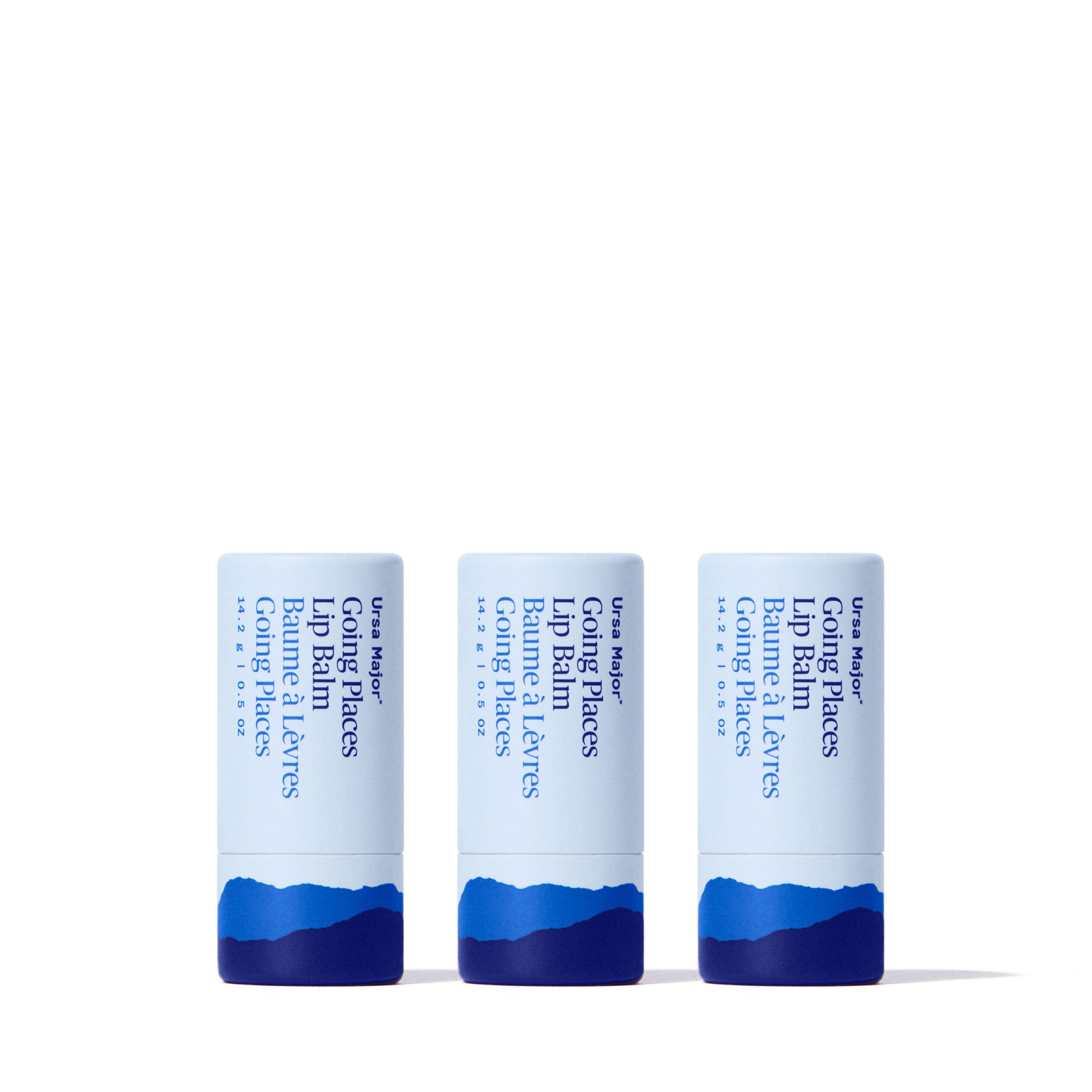 Three tubes of Ursa Major Going Places Lip Balm with blue and white packaging on a white background