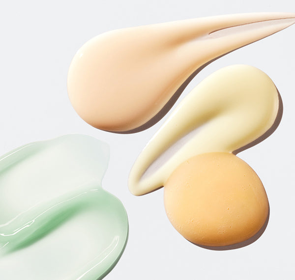 Image of pale-green, honey, and beige skincare product swatches spread on a gray background