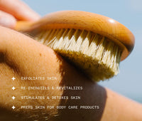 Hand smoothing wooden Dry Brush against skin with text about its benefits, including: Exfoliates skin; Re-energizes and revitalizes; Stimulates and detoxes skin; Preps skin for body care products