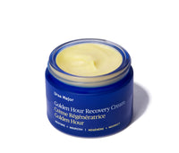 Opened jar of Ursa Major Golden Hour Recovery Cream on a white background