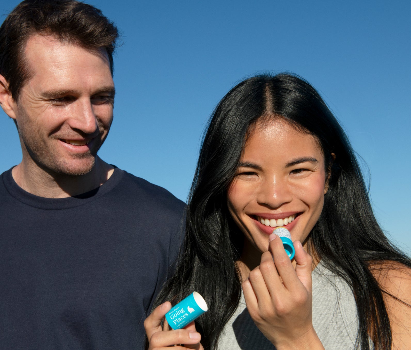 Man and woman smiling applying lip balm