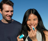 Man and woman smiling applying lip balm