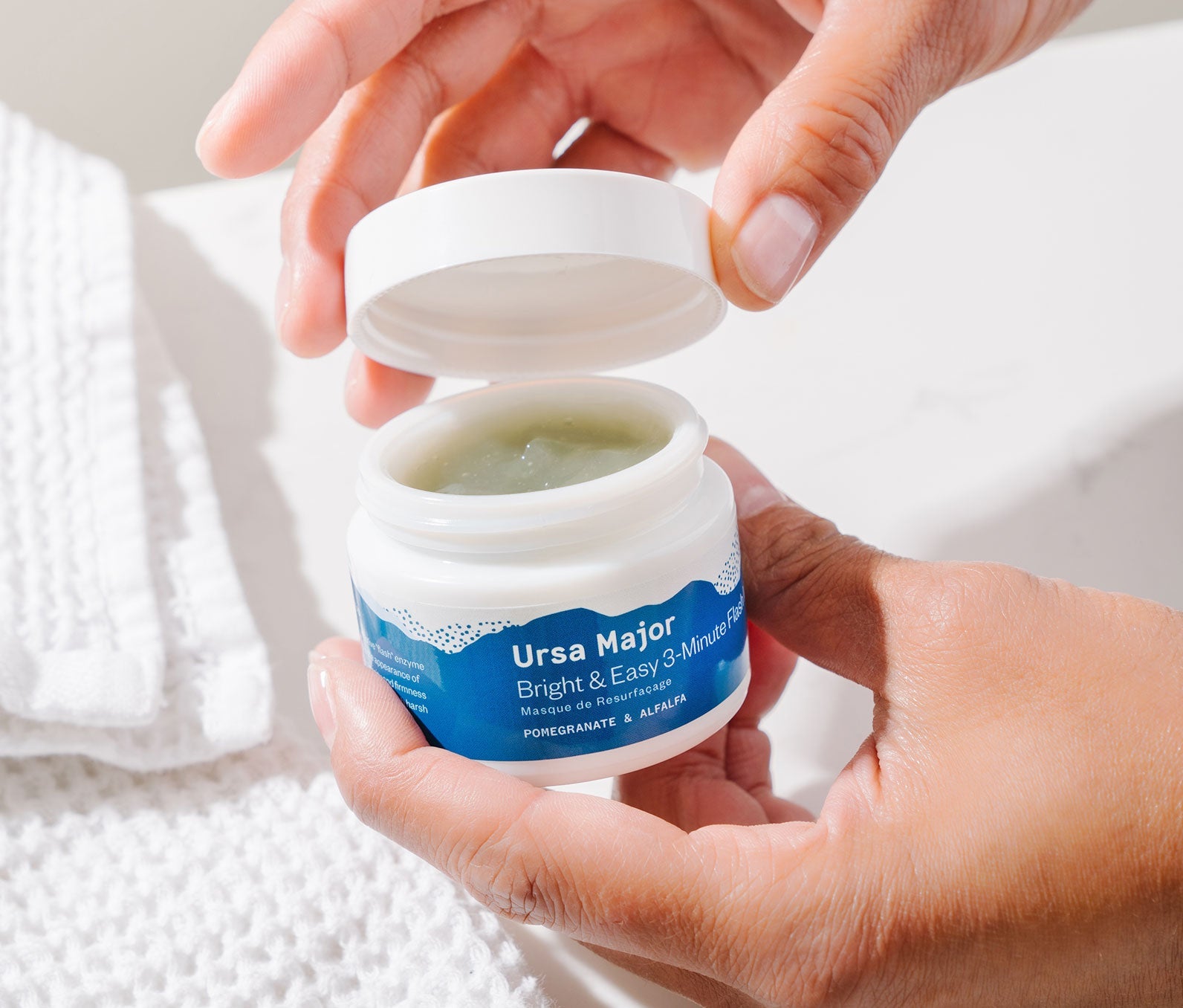 Person opening a jar of Bright & Easy 3-Minute Flash Mask.  Inside the car is a pale green mask consistency.