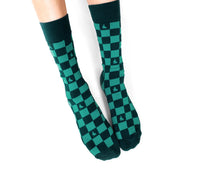 Green and black checkered socks worn by a person on a white background