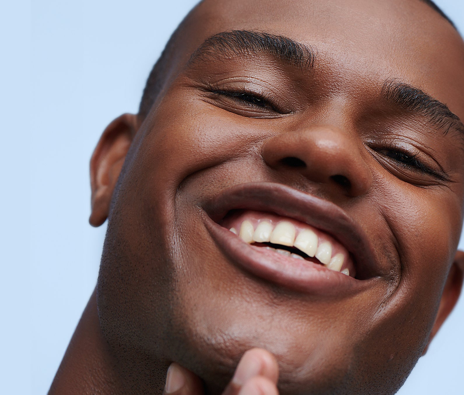 Close-up of a smiling man with bright and smooth skin, showcasing the effects of using a vitamin C serum for brightening.