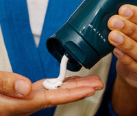 Person squeezing Ursa Major Stellar Shave Cream onto their hand.