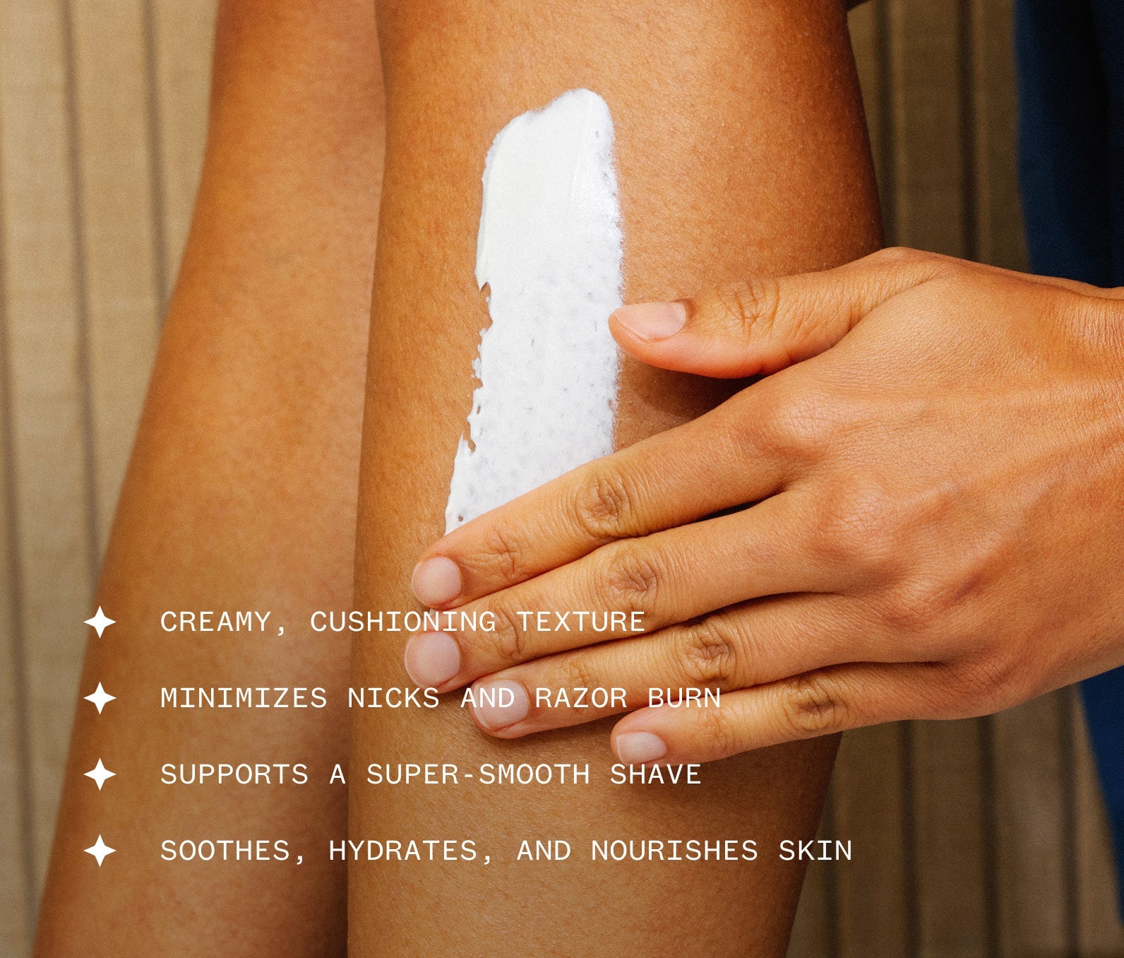 Hand applying Ursa Major Stellar Shave Cream to their leg.  Text on image reads that the product has a creamy, cushioning texture, minimizes nicks and razon burn, supports a supersmooth shave, soothes, hydrates, and nourishes skin.