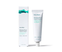 Box of Ursa Major Botanic Buzz Hand Cream next to the tube on a white background.