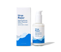 Box of Ursa Major Making Milky Cleanser next to the bottle on a white background.  Box and jar are white with blue lettering and blue mountains.