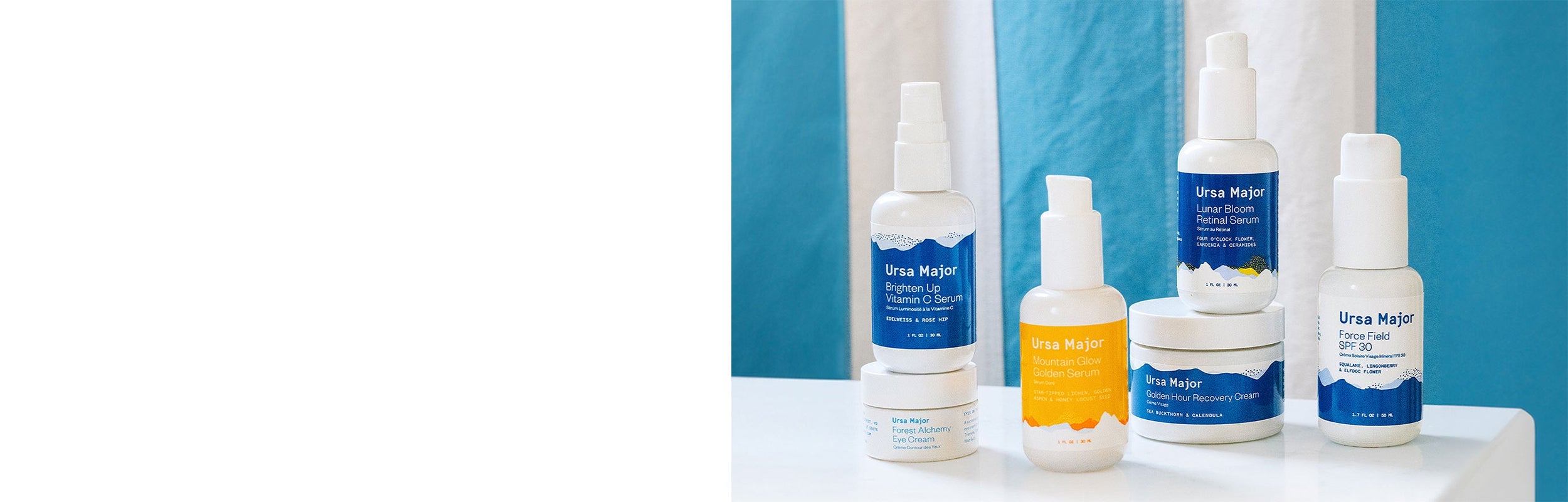 Bottle of Ursa Major Brighten Up Vitamin C Serum, jar of Forest Alchemy Eye Cream, bottle of Mountain Glow Golden Serum, bottle of Lunar Bloom Retinal Serum, jar of Golden Hour Recovery Cream, and jar of Force Field SPF on a table with a white and blue stripped background