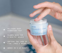 Hand holding a blue jar of Ursa Major Vital Spring Hydration Mask on a blurred natural background with text of product details, including: Delivers deep hydration fast; Plumps skin for a healthy bounce; Softens the look of fine line and wrinkles; Works in 5-10 minutes