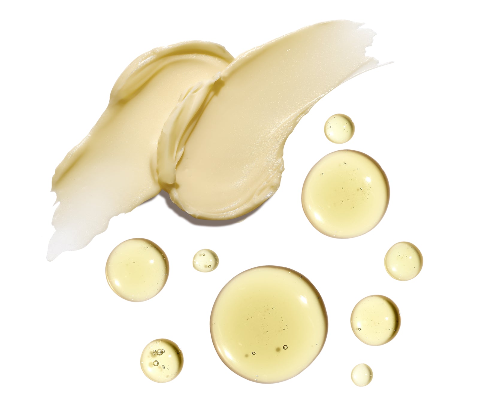 Thick yellow cream next to yellow oil droplets on a white background
