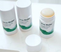 Three tubes of Ursa Major Hoppin' Fresh Deodorant on a white countertop  The right tube is open and the cap is to the side.