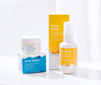 Mountain Glow Golden Serum and Forest Alchemy Eye Cream on a white counter with a white wall behind it.